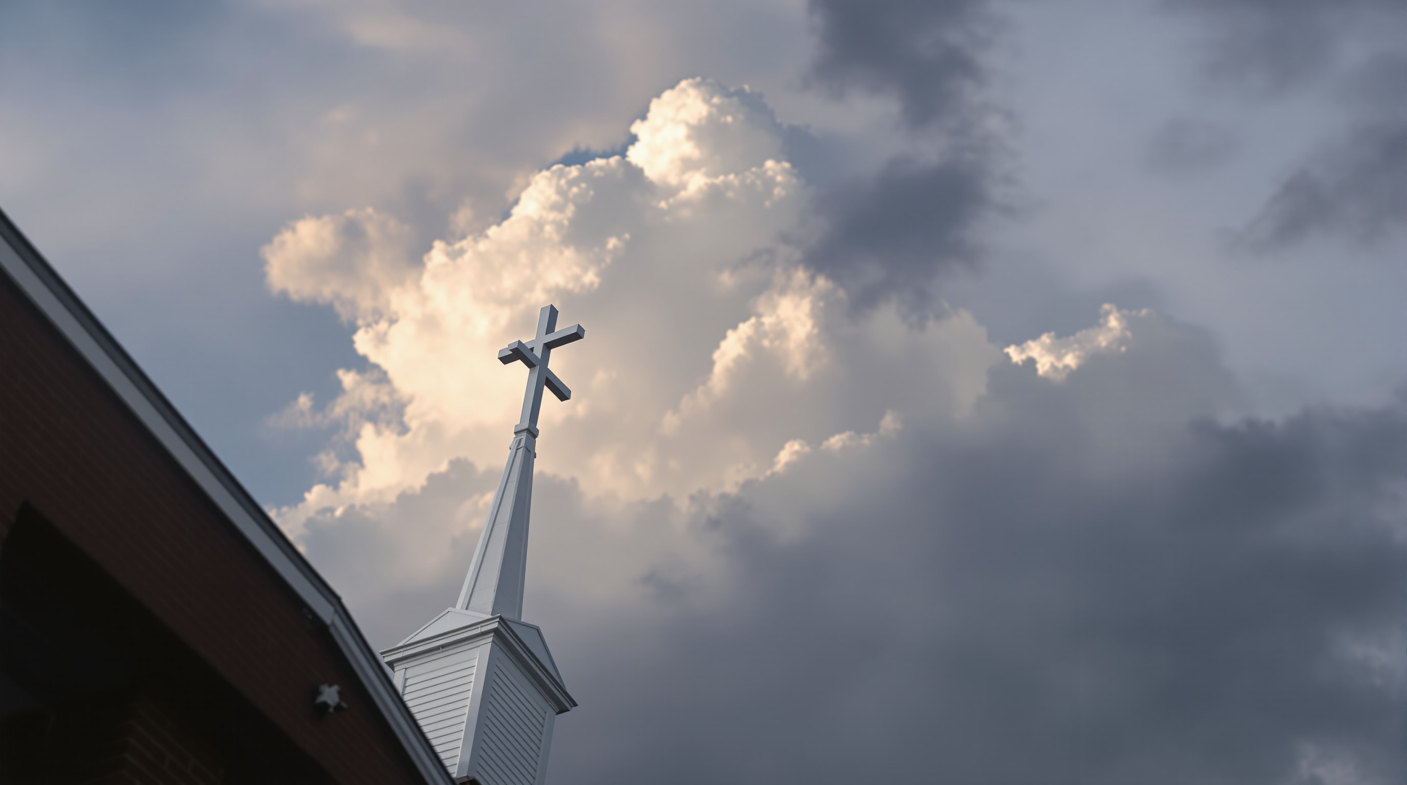 A white church spire and cross rising against a wide north Texas sky