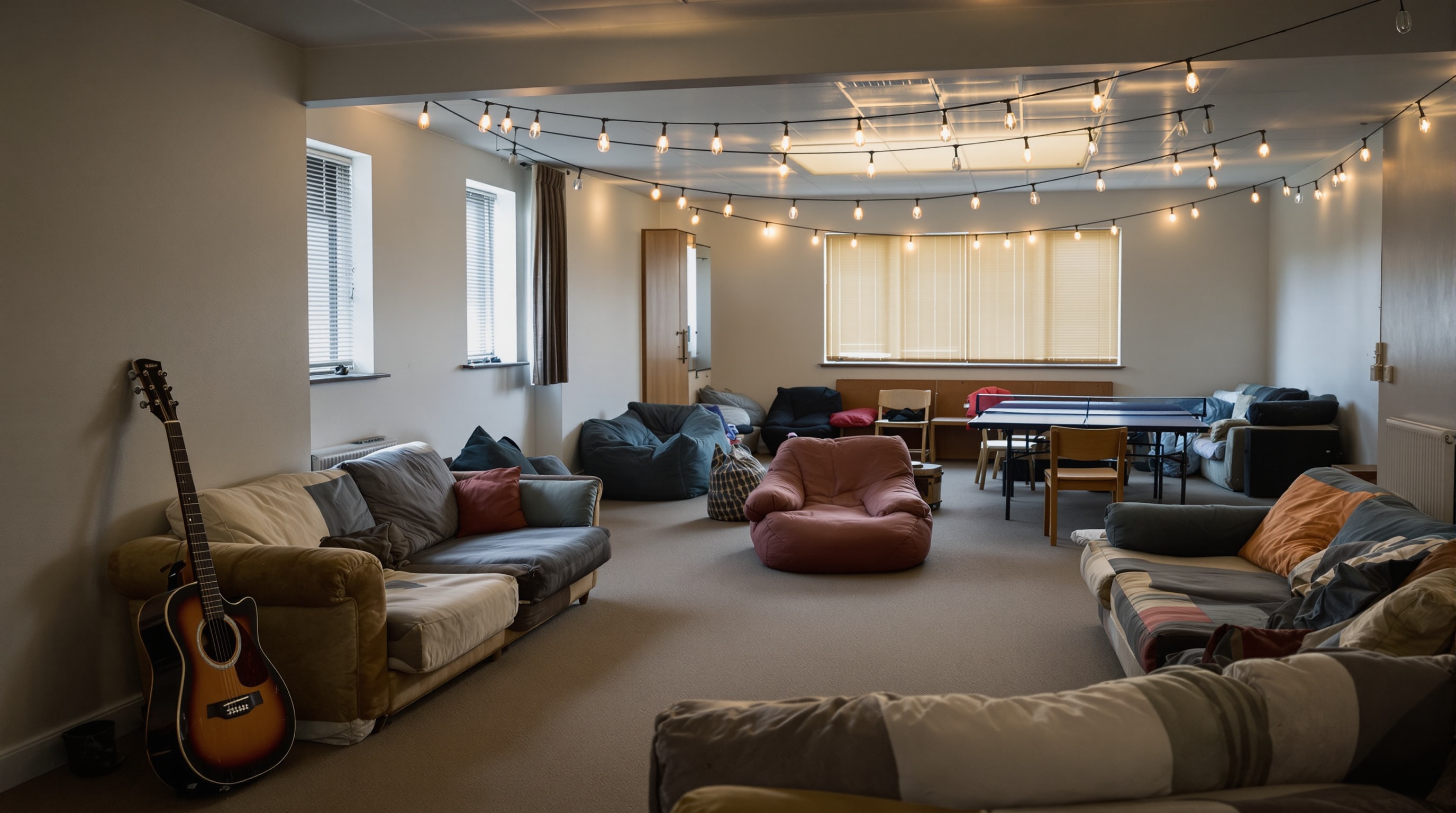 An empty church youth room with second-hand sofas, a guitar and a ping-pong table